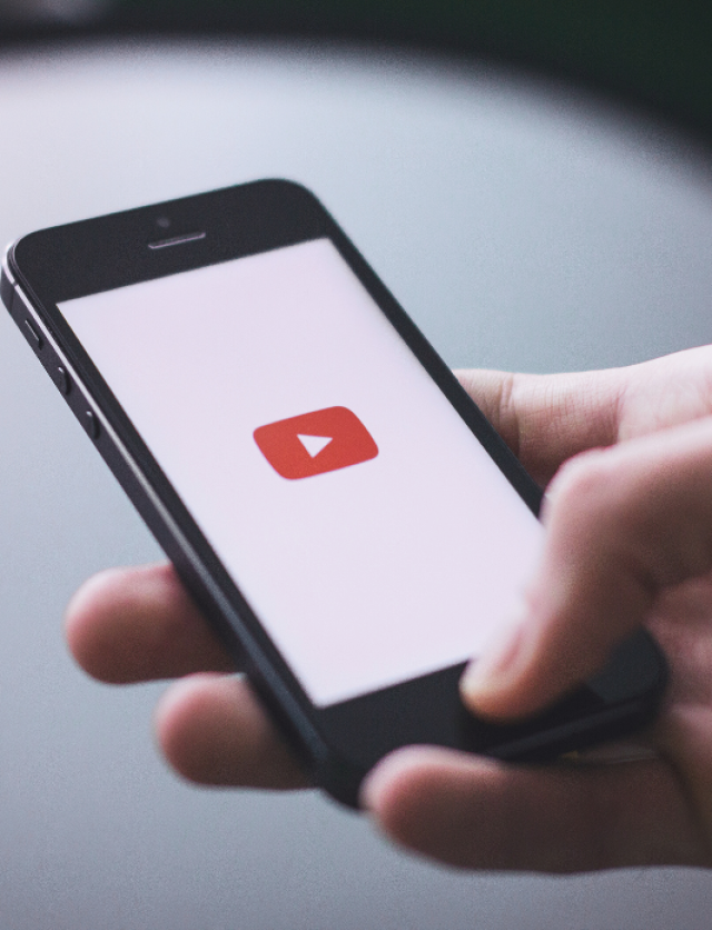 a hand with a mobile phone showing YouTube icon on the screen, representing YouTube product